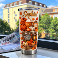 Custom stainless steel tumbler featuring autumn designs placed on a windowsill with a newspaper and buildings.