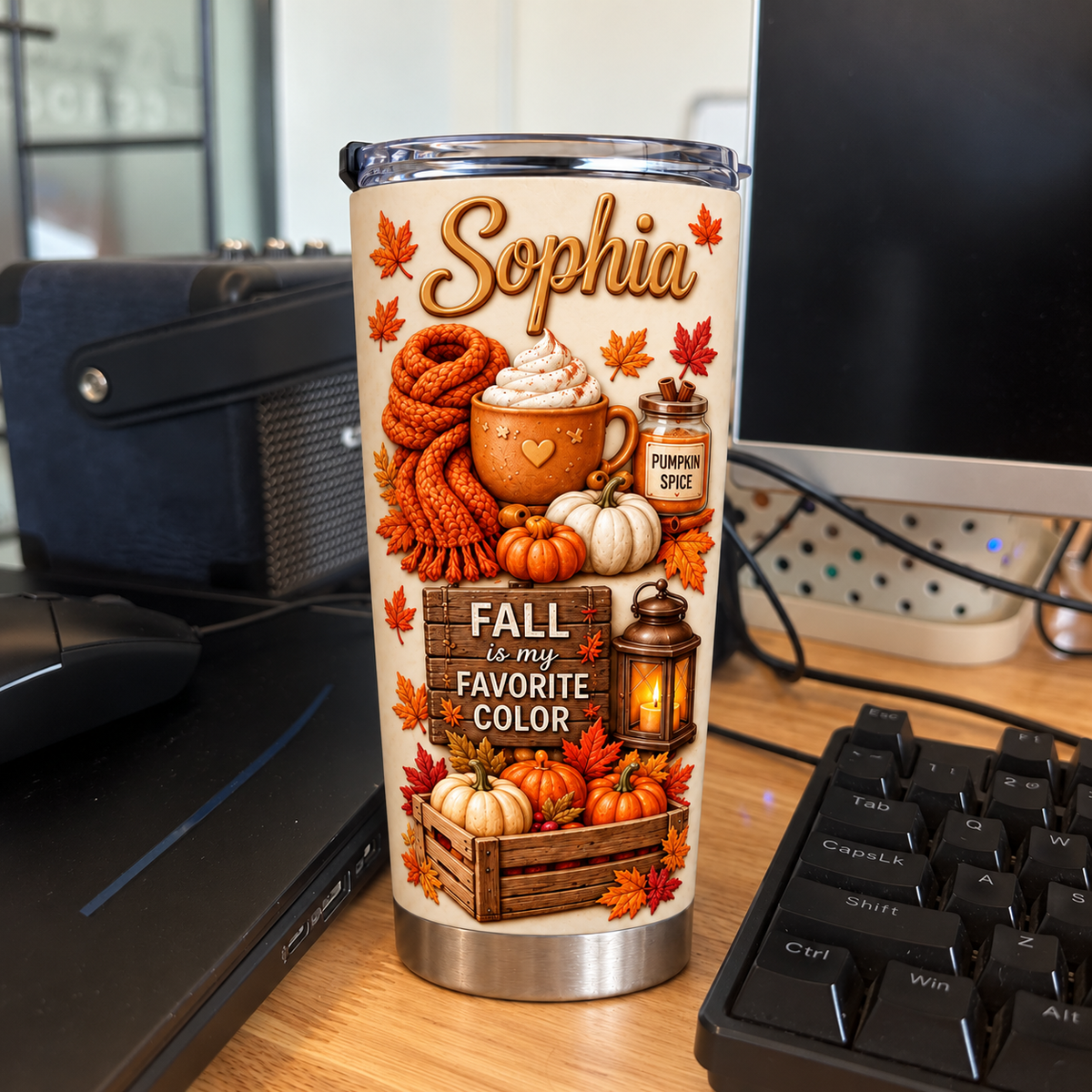 Personalized stainless steel tumbler featuring seasonal autumn designs standing near a computer keyboard.