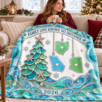 Woman holds a mug on a sofa with the Family Love Knows No Distance Blanket featuring state ornaments and a teal tree.