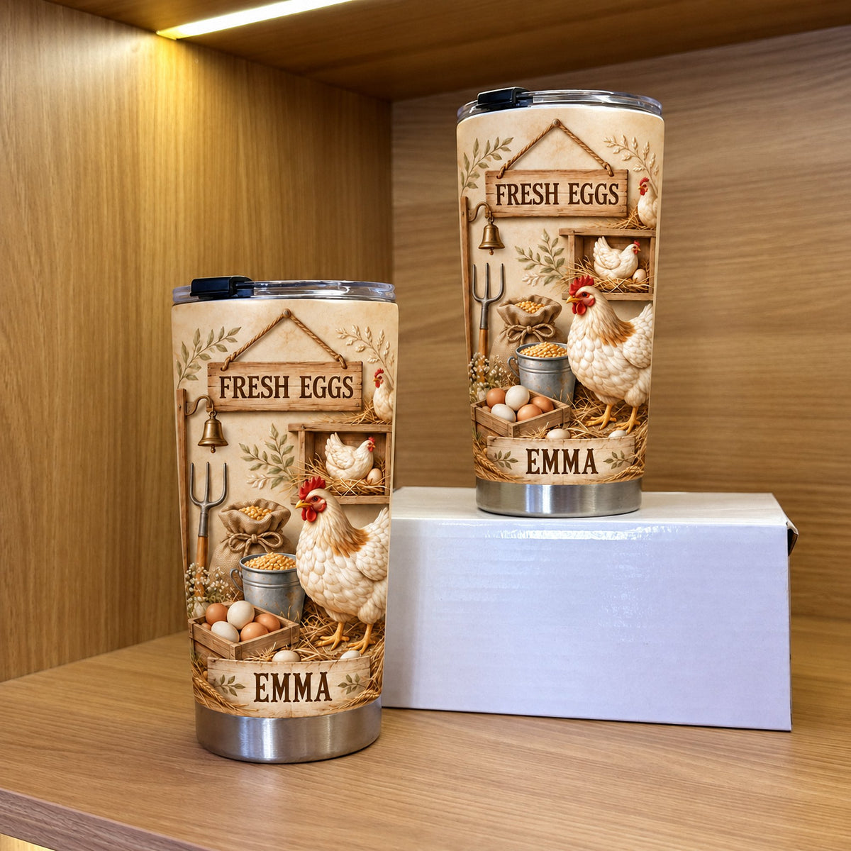 Two personalized Farm Fresh Eggs tumblers in 20oz and 40oz sizes displayed on a wooden shelf next to a white box.