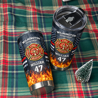 Two personalized firefighter tumblers displayed on a green and red plaid fabric next to a miniature Christmas tree.