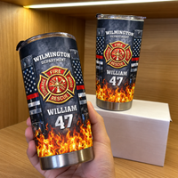 Hand holding a personalized stainless steel travel tumbler with fire rescue design next to a second tumbler on a white box.