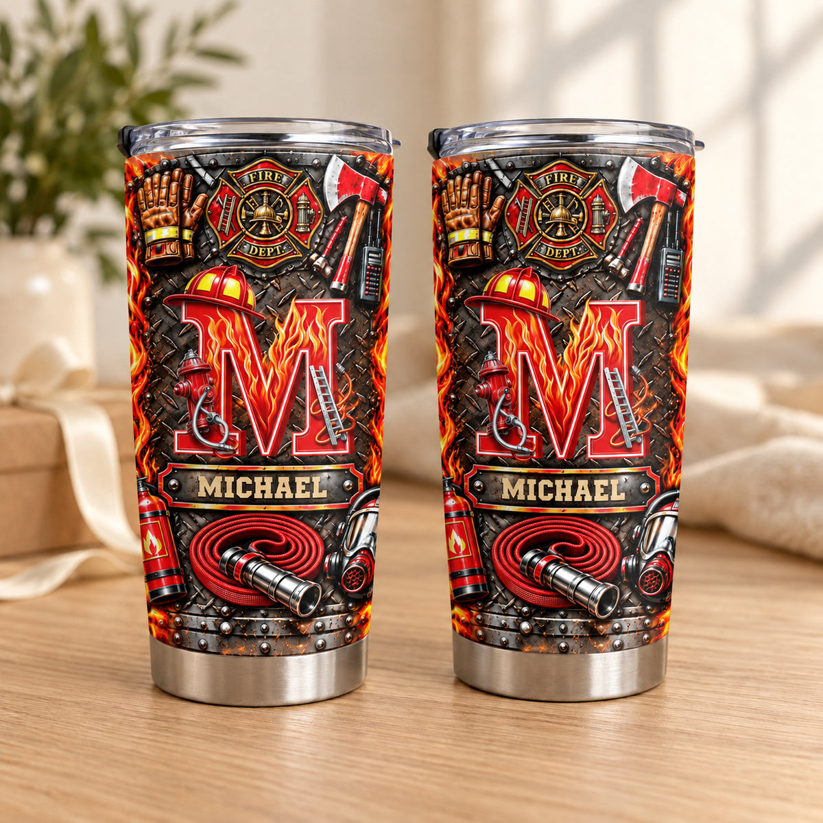 Two personalized firefighter initial name tumblers stand upright on a wooden table with a blurred plant background.