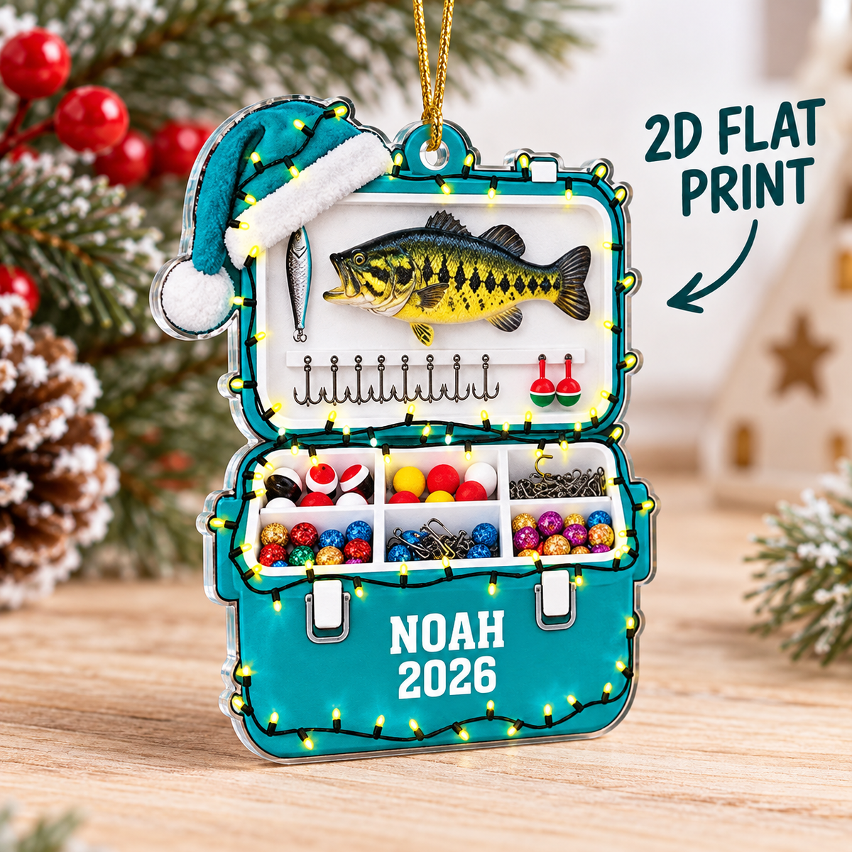 Teal acrylic christmas ornament shaped like a tackle box with bass fish graphic and NOAH 2026 text, showing 2D flat print