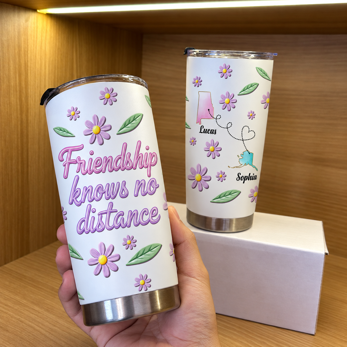 A hand holding a white custom name travel mug with purple daisies, showing the friendship quote next to another distant