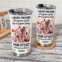 Two personalized funny hairstylist tumblers standing on a textured surface with a tiled wall backdrop.