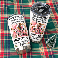Two personalized funny hairstylist tumblers displayed on a green plaid fabric with a small decorative tree.