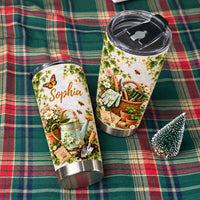 Two gardening theme personalized tumblers displayed on a green plaid fabric cloth next to a miniature evergreen tree.