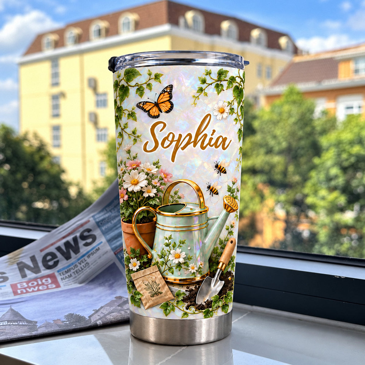 Botanical tumbler featuring custom name Sophia and garden tools displayed on a windowsill with a newspaper and buildings