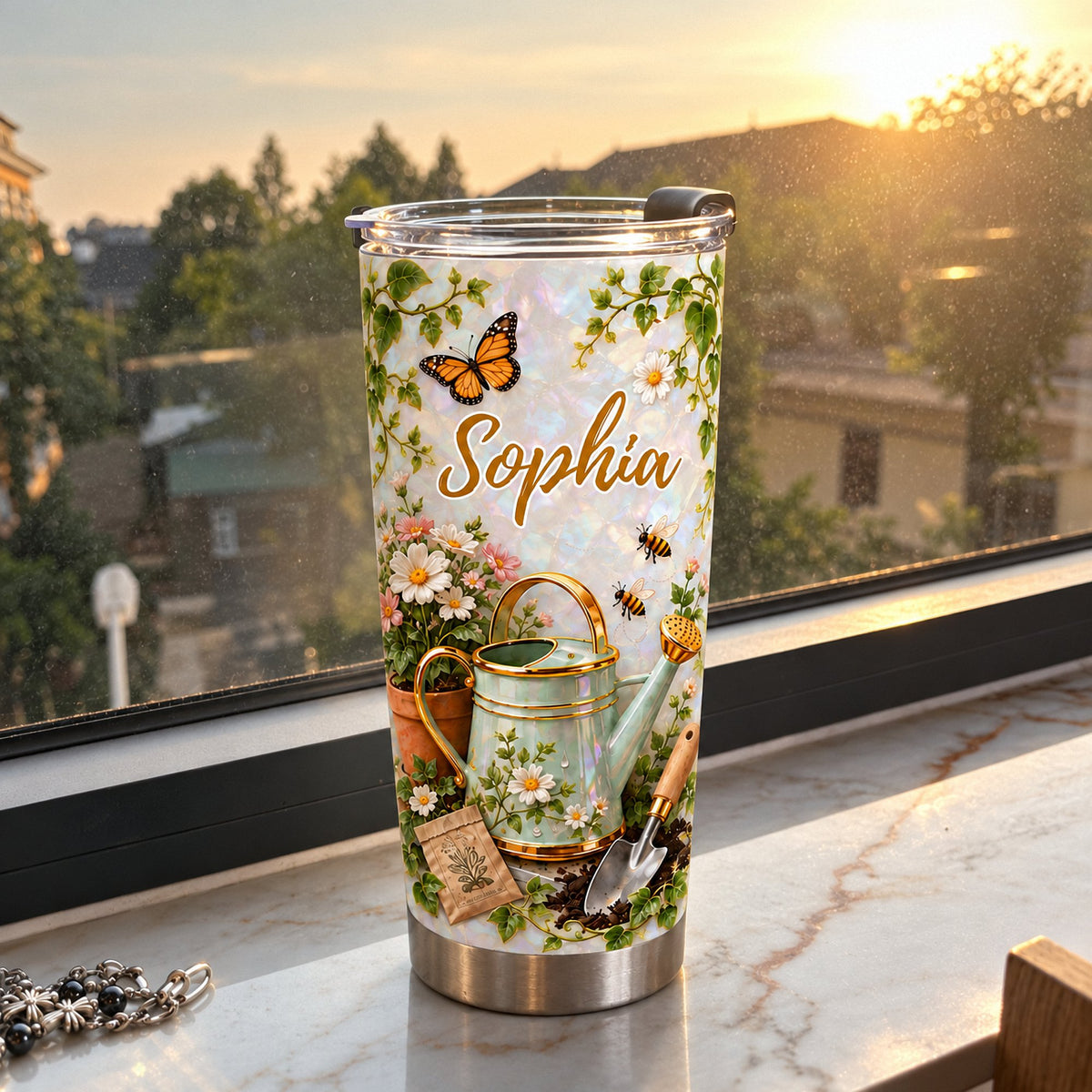 Gardening theme personalized tumbler with watering can design sitting on a windowsill during a warm sunny afternoon.