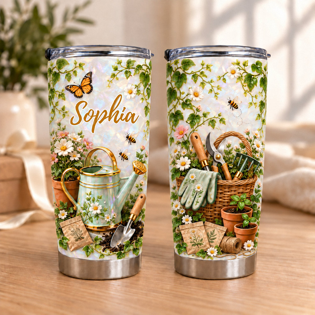 Two pearlescent white stainless steel tumblers showing a vintage gardening illustration with ivy, daisies, butterflies, bees