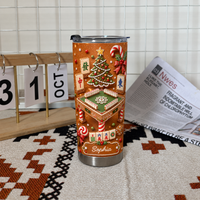 A custom name tumbler featuring gingerbread mahjong design next to a wooden perpetual calendar and newspaper.