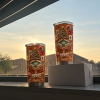 Two gingerbread mahjong Christmas tumblers displayed on a windowsill during a golden sunset.