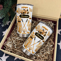Two personalized golf tumblers arranged in a gift box lined with paper shreds.