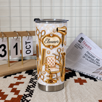 A cosmetologist gift stainless steel travel mug sits on a textured mat next to a calendar and a newspaper.