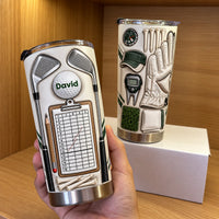 Personalized golf tumbler with crossed irons and a scorecard design displayed on a wooden shelf.