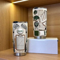 Two insulated golf mugs displaying custom name details, posed on a wooden shelf with warm lighting.