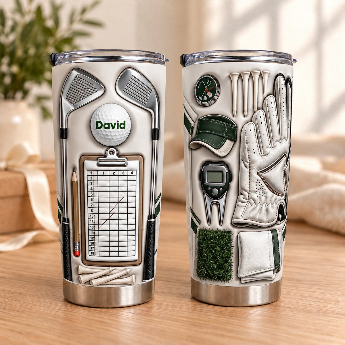 Two beige stainless steel tumblers showing golf gear print with crossed irons, scorecard, golf ball reading David, glove, and