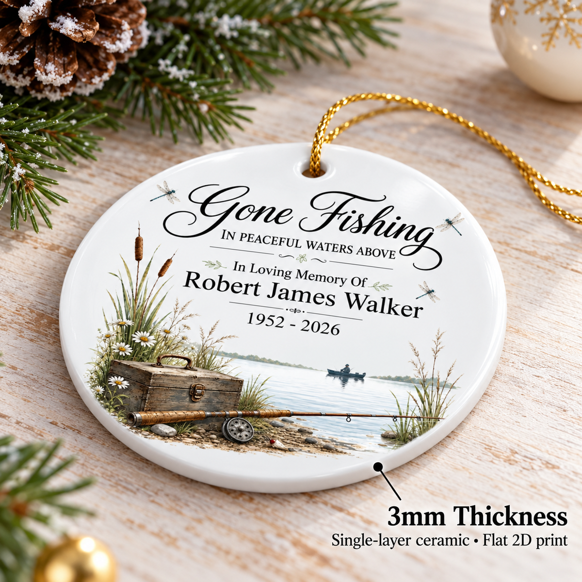 Round memorial fishing ornament lying flat on a wooden table with a pine branch and 3mm thickness text