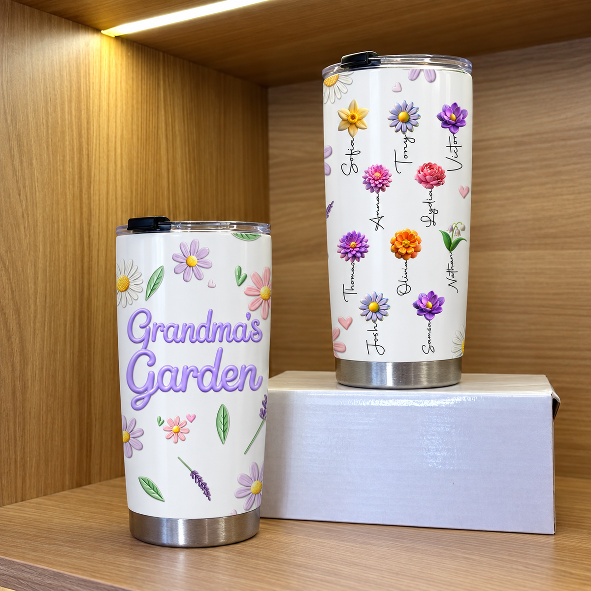 Two white birth flower tumblers displayed inside a wooden shelf with warm lighting.