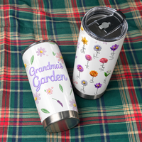 Two personalized insulated tumblers resting on a green and red plaid fabric surface.
