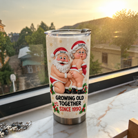 Stainless steel tumbler showing cartoon Santa and Mrs. Claus in underwear sitting on a windowsill at sunset.