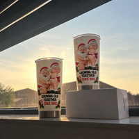 Two custom size stainless steel tumblers featuring humorous Santa art on a windowsill overlooking rooftops.