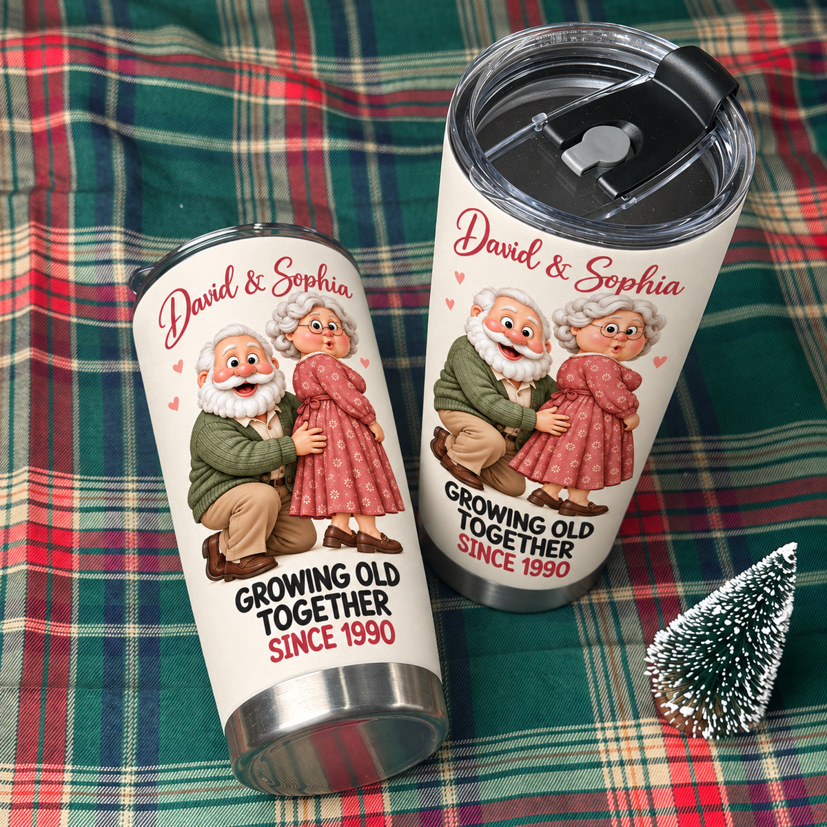 Two white stainless steel travel tumblers with an elderly couple graphic and David & Sophia text resting on a red and green