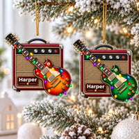 Two personalized guitar amp acrylic Christmas ornaments hanging on a snowy Christmas tree, one red and one green.