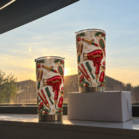 Two personalized hair stylist tumblers with festive salon designs sit on a box by a window during a warm sunset glow.