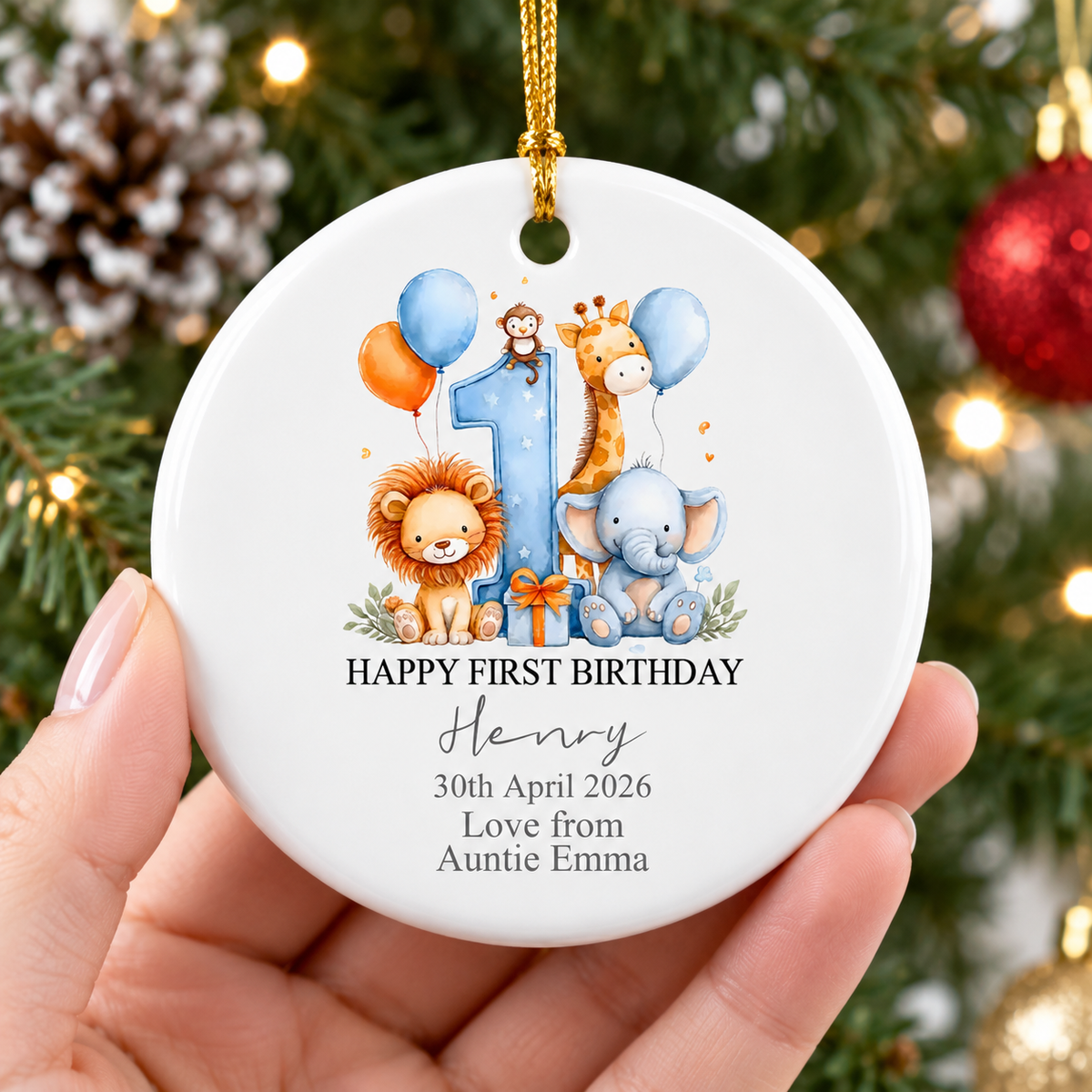 Hand holding the personalized baby gift ornament with a watercolor safari jungle design against a pine tree background.