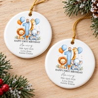 Two personalized baby gift ceramic ornaments resting side by side on a wooden table with pine greenery.