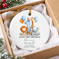 Happy First Birthday ornament packaged securely inside a brown cardboard gift box lined with white tissue paper.