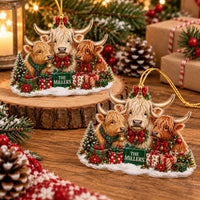 Two Highland Cow Family Christmas Ornaments displayed together on a wooden slice and table with pine decor.