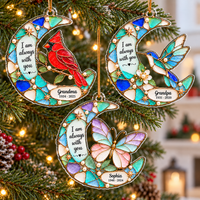 Three custom memorial ornaments hanging on a pine tree branch with fairy lights, showing cardinal, hummingbird, and butterfly