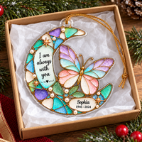 A pastel butterfly memorial ornament with custom name and dates resting inside an open gift box with tissue paper.