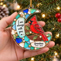 Hand holding the flat acrylic cardinal bird ornament against a blurred background with Christmas tree lights.