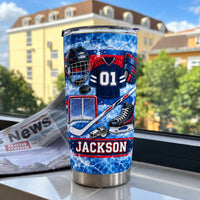Ice Hockey Equipment Collage Tumbler standing on a white sill against a blurred city and green tree background view.