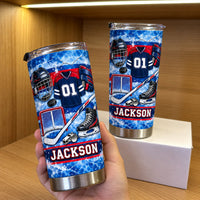 Two personalized hockey gear tumblers displayed on a wooden shelf with warm lighting inside a wooden display cabinet.