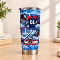 Ice Hockey Equipment Collage Tumbler with blue cracked ice pattern and custom name placed upright on a wooden table.