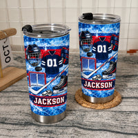 Two custom sports equipment collage tumblers with black lids displayed on a textured gray countertop near a kitchen calendar.