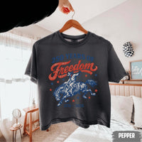 A dark charcoal pepper-colored t-shirt hanging on a wooden hanger with a distressed patriotic cowboy design.
