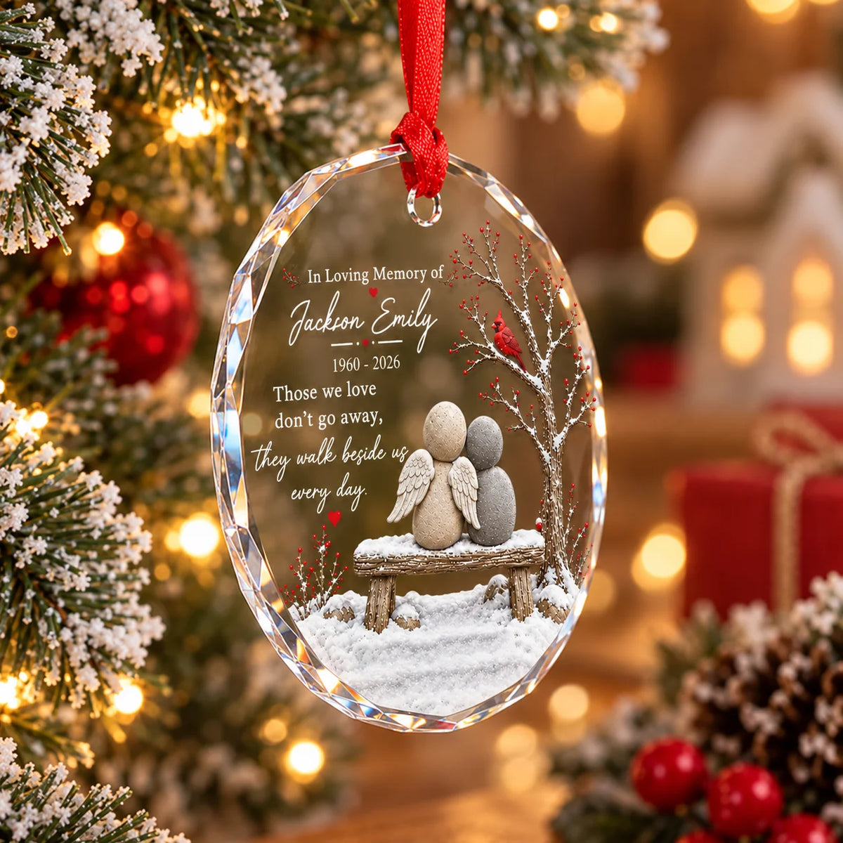 Personalized glass ornament hanging on holiday tree branch, featuring pebble angel bench design.
