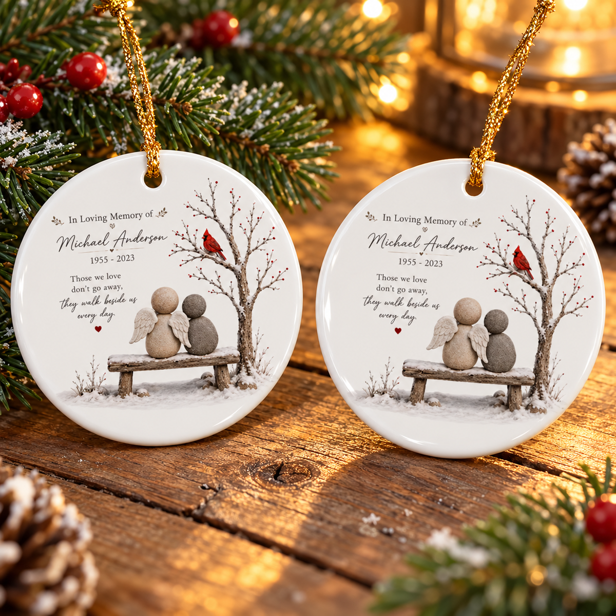 Two personalized sympathy ornaments displayed side by side on a rustic wooden surface with pine branches.