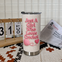 Personalized insulated stainless steel cup standing on patterned textile next to calendar block and newspaper.