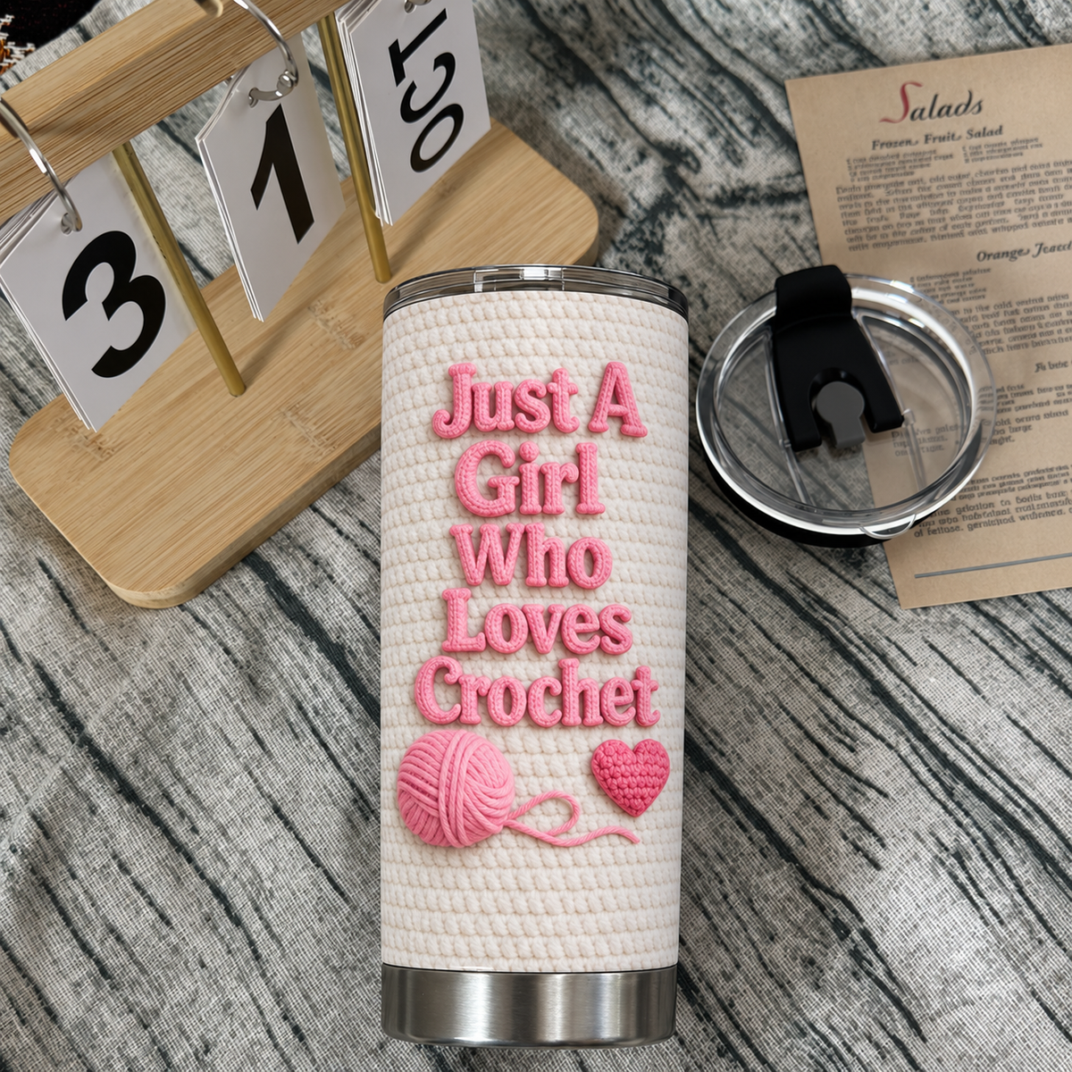 Personalized insulated stainless steel cup laid flat on wooden surface with open lid, calendar, and food recipe note.