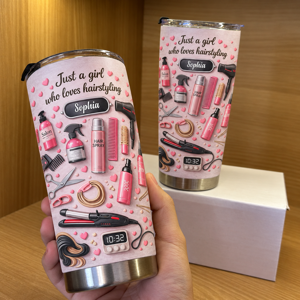 A hand holding a pink custom name tumbler for a cosmetologist in front of a wooden shelf.