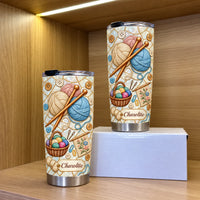 Two personalized stainless steel tumblers with knitting yarn design displayed on a white box inside a wooden shelf.