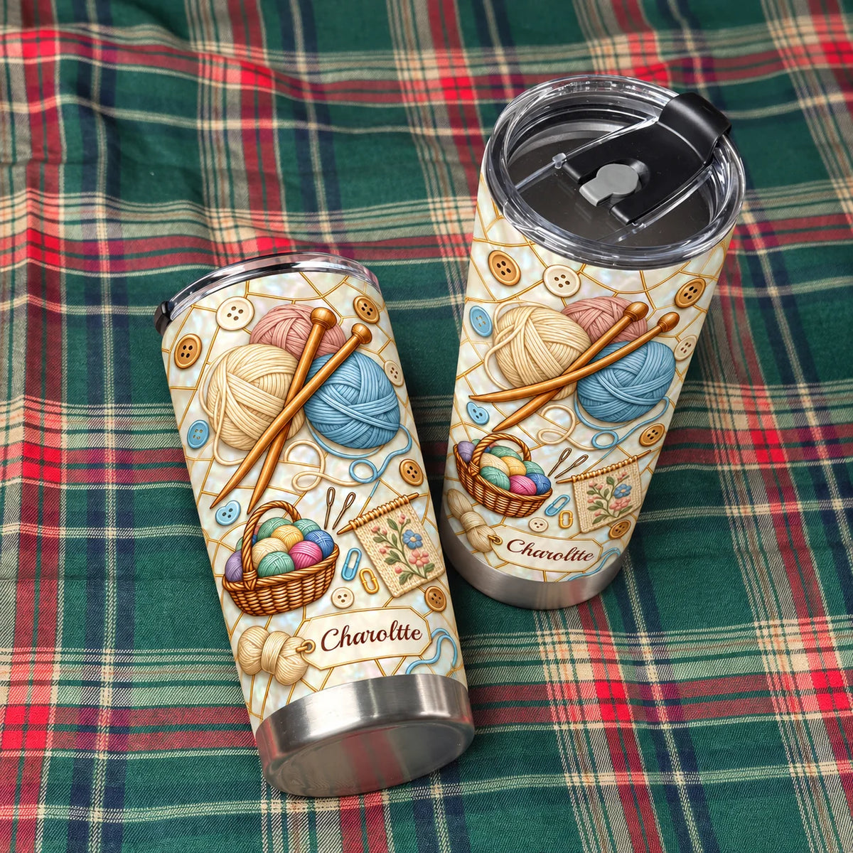 Two knitting yarn stainless steel tumblers laid out on a green and red plaid fabric surface.