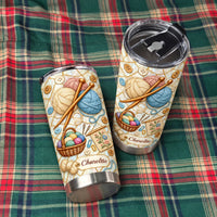 Two knitting yarn stainless steel tumblers laid out on a green and red plaid fabric surface.